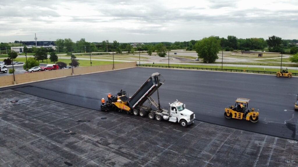 rose paving trucks laying fresh asphalt in a parking lot